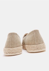 Beige Leinen-Esparzilles mit einer Sohle aus Juteseil und strukturiertem Stoff, ausgestattet mit einem abgerundeten Rücken und einem schlichten Design.