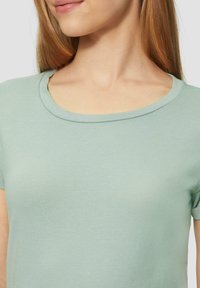 T-shirt vert menthe avec un col rond et des manches courtes. Fabriqué en tissu doux, doté d'une texture lisse et d'une coupe ajustée.