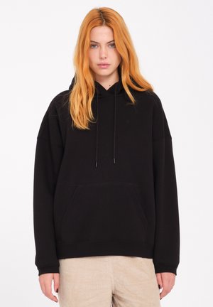 Sudadera negra con un bolsillo frontal tipo pouch, capucha con cordón y mangas de corte holgado. La tela parece suave con una textura lisa.