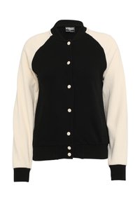 Veste varsity noire et blanche avec corps noir, manches blanches, fermeture boutonnée devant, poignets, col et bas côtelés.