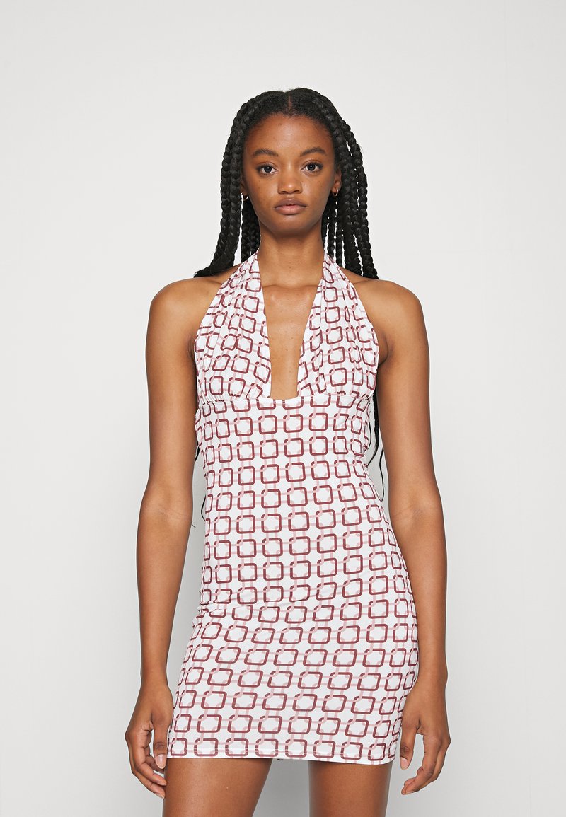 Vestido mini com alças de pescoço, feito de tecido elástico, apresentando um fundo branco com padrões geométricos vermelhos, decote profundo e silhueta justa.