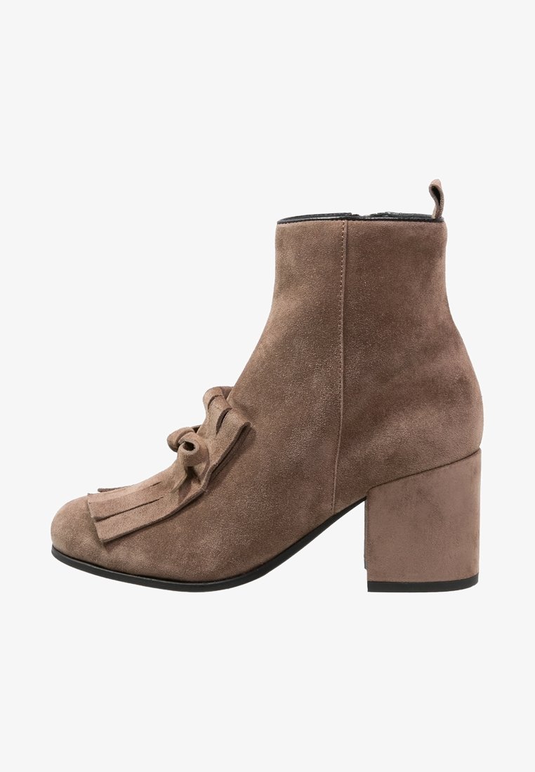 Bottine en daim marron avec talon bloc, franges décoratives et détail nœud à l'avant, fermeture éclair latérale.