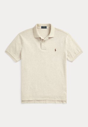 Beige polo skjorte laget av bomull, med en placket med to knapper, korte ermer, og en liten brun brodert logo på venstre bryst.