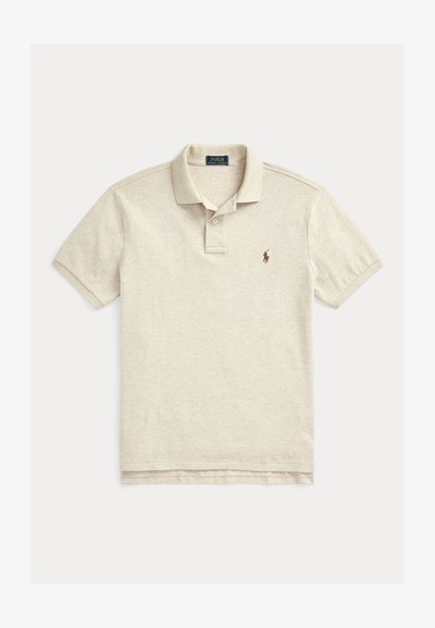 Polo beje feito de algodão, com uma pala de dois botões, mangas curtas e um pequeno logótipo bordado castanho no lado esquerdo do peito.