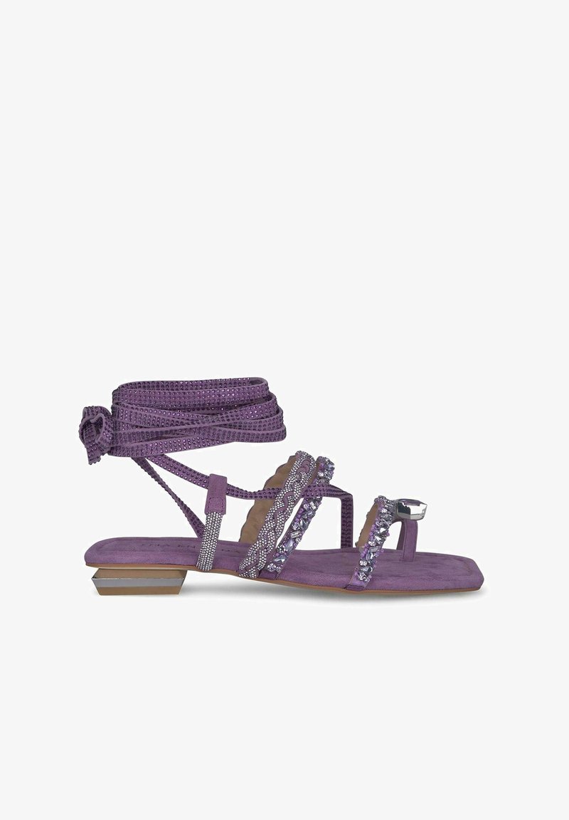 Lila Wildledersandale mit dünnen Riemen, verziert mit Kristallen und einem geknoteten Knöchelriemen. Hat einen niedrigen Blockabsatz und eine strukturierte Sohle.