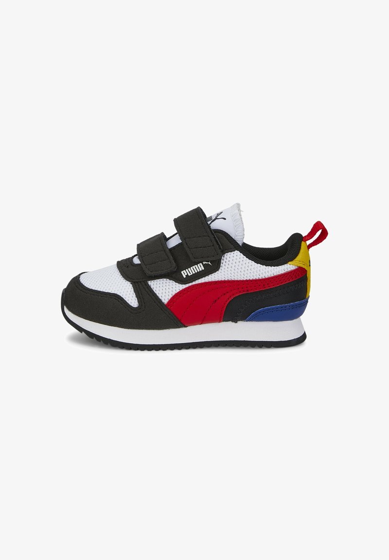 Baskets pour enfant Puma avec maille blanche, superpositions noires, bande latérale rouge, accents bleu et jaune au niveau du talon, et straps Velcro noirs sur une semelle blanche.
