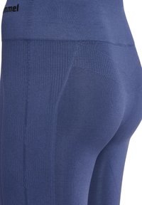 Marineblaue Leggings aus elastischem Material mit einem strukturierten Design, das abwechselnd gerippte und glatte Bereiche aufweist, elastischer Bund.