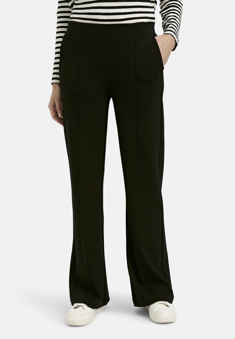 Schwarze, weit geschnittene Hose mit glatter Textur, seitlichen Taschen und hohem Bund. Tragen mit einem gestreiften Langarmoberteil.