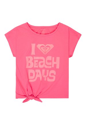 Chemise rose à manches courtes avec nœud à l'avant et texte "I [cœur] Journées à la plage" ainsi que logo en police rose plus claire.