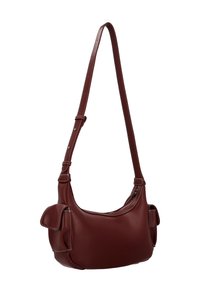Skórzana torba na ramię w ciemnoczerwonym kolorze o gładkim wykończeniu, o zaokrąglonym kształcie, z regulowanym paskiem i zewnętrznymi kieszeniami na klapki.