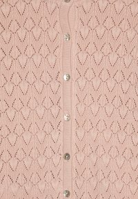 Ljusrosa stickad cardigan med ett intrikat diamantmönster, runda knappar och ribbade kanter. Lämplig för att användas i olika stilar.