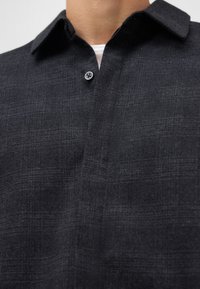 Donkergrijze button-up overhemd van een gestructureerde stof, voorzien van een kraag en een enkele knoopsluiting, met een subtiel geweven patroon en een rechte snit.