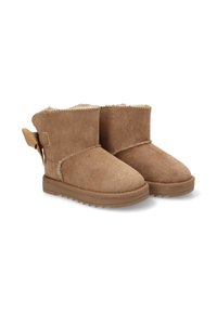 Botas de tobillo de ante color tan con un interior suave y esponjoso, punteras redondeadas y suelas acanaladas. Presentan una correa decorativa y un botón en la parte trasera.