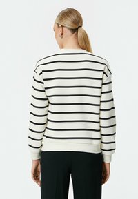 Bomullströja med horisontella svartvita ränder, ribbade ärmslut och nederkant, samt en avslappnad passform med rundad halsringning.