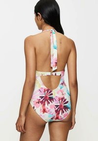 Bañador de una pieza con un patrón floral de múltiples colores, con cuello halter, diseño de espalda abierta y detalles recortados en los lados.