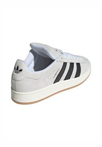 Sivi sužni tenisice s bijelim vezicama, crnim kožnim prugama i gumiranim potplatom. Imaju strukturirani stražnji panel i oznaku "CAMPUS".