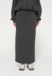 Dunkelgraßer langer Rock aus weichem, strukturiertem Stoff mit einem elastischen Bund und Kordelzug, kombiniert mit lässigen Sneakers.