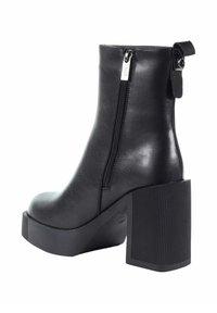 Czarne botki za kostkę z ekoskóry z masywnym żebrowanym obcasem, z boku zapinane na zamek błyskawiczny oraz z dekoracyjnym paskiem z metalowym akcentem z tyłu.