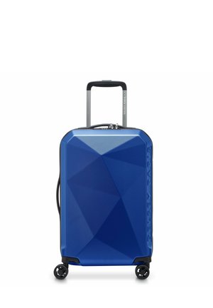 Valise rigide bleue au design angulaire, surface texturée, poignée télescopique et quatre roues noires pour la mobilité.