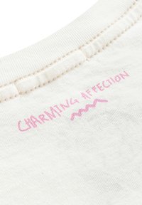 Bawełniany t-shirt z zaokrąglonym dekoltem, z nadrukiem "CHARMING AFFECTION" na różowo, z falistym detalem poniżej na kremowym tle.