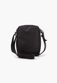 Compact black crossbody bag made of textured fabric, featuring a zip closure and adjustable strap for convenience.