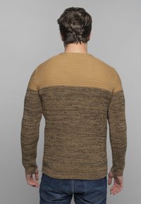 Langdurige gebreide trui met een gestructureerd bruin ontwerp en een effen tan bovenstuk. De pasvorm is relaxed met geribbelde manchetten.