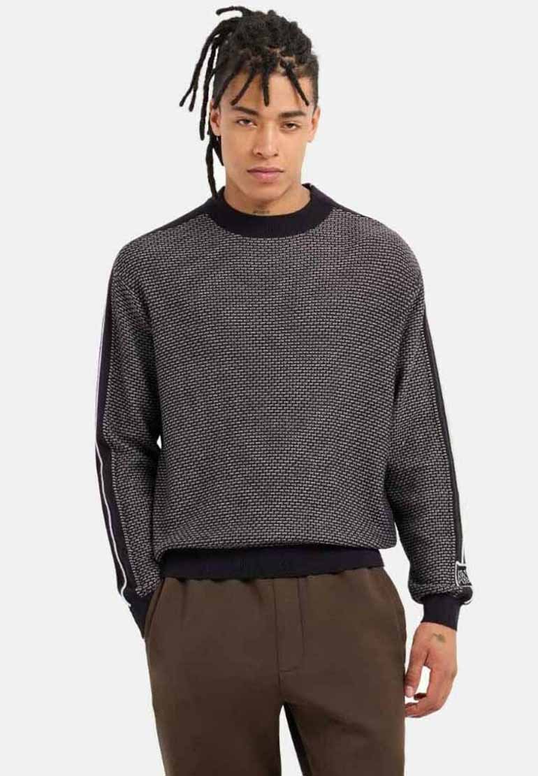 Maglione lavorato a maglia di colore grigio scuro con un motivo testurizzato, caratterizzato da polsini e orlo a coste neri, con strisce laterali a contrasto.