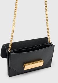 Borsa a mano in pelle nera con tracolla in catena dorata, dotata di una chiusura rettangolare dorata e più scomparti. Texture liscia e design strutturato.