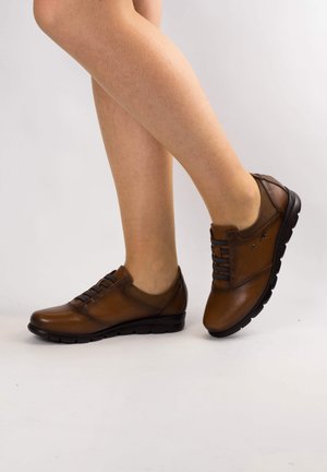Chaussures en cuir marron avec une finition lisse, à lacets à l'avant et semelle en caoutchouc noire ; elles présentent un profil bas et un design à bout arrondi.