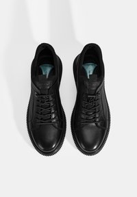 Baskets en cuir noir avec une texture lisse, dotées de lacets, d'une languette et d'une semelle en caoutchouc. Doublure intérieure bleue avec le texte "CONFORT".