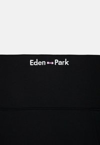 Un sweat-shirt noir avec le texte brodé en blanc "Eden Park" et un accent de nœud papillon rose, fabriqué dans un tissu doux et texturé.