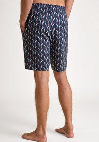Heren zwemshorts in marineblauw met elastische tailleband en zijzakken. Ze hebben een herhalend patroon van grijze flamingo's met rode accenten op een donkere achtergrond.