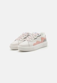 White sneaker featuring a smooth leather upper, pink suede accent, textured gray details, and patterned laces. Thick rubber sole.