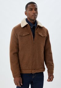 Brown wool blend jacket with a sherpa collar, zip closure, and two chest pockets. Textured fabric with a buttoned hem and cuffs.