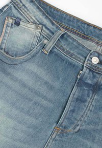 Vaqueros de denim azul desgastado con un diseño clásico de cinco bolsillos, que presentan costuras en contraste y cierre de botón metálico en la cintura.