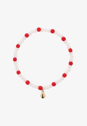 Joustorannekoru, jossa vuorottelevat punaiset ja valkoiset pyöreät helmet ja pieni kultainen pisaranmuotoinen riipus.