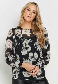 Blusa nera con maniche lunghe trasparenti e motivo floreale in tonalità di bianco e grigio. Presenta un colletto rotondo e polsini con bottoni. Texture liscia.