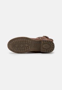 Bottine en cuir marron avec une surface texturée, semelle en caoutchouc robuste dotée de motifs de traction, et accents en métal pour la fermeture.