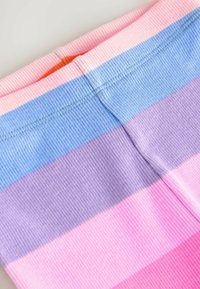Leggings iz rebrastim materialom s horizontalnimi črtami v roza, svetlo modri, sivki in vijolični barvi. Imajo mehak, elastičen pas.