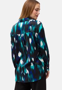 Camicia a maniche lunghe con un vivido motivo astratto blu e verde su sfondo nero; realizzata in tessuto leggero e morbido con polsini a bottone.
