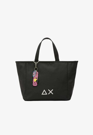 Sac fourre-tout noir en nylon, doté de poignées doubles, avec un logo géométrique blanc et des charms colorés attachés à un porte-clés.