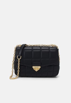 Zwarte doorgestikte leren crossbodytas met gouden kettingriem en gouden sluiting gegraveerd met "Michael Kors" op de voorklep.