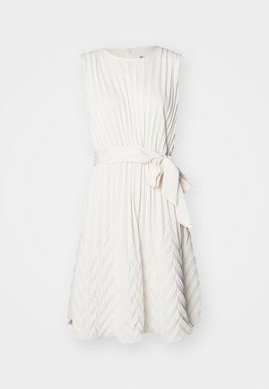 Bijela haljina bez rukava s vertikalnim nabranjima, pojasom u struku i suknjom koja se širi. Ima okrugli izrez i zatvaranje na leđima sa zatvaračem.