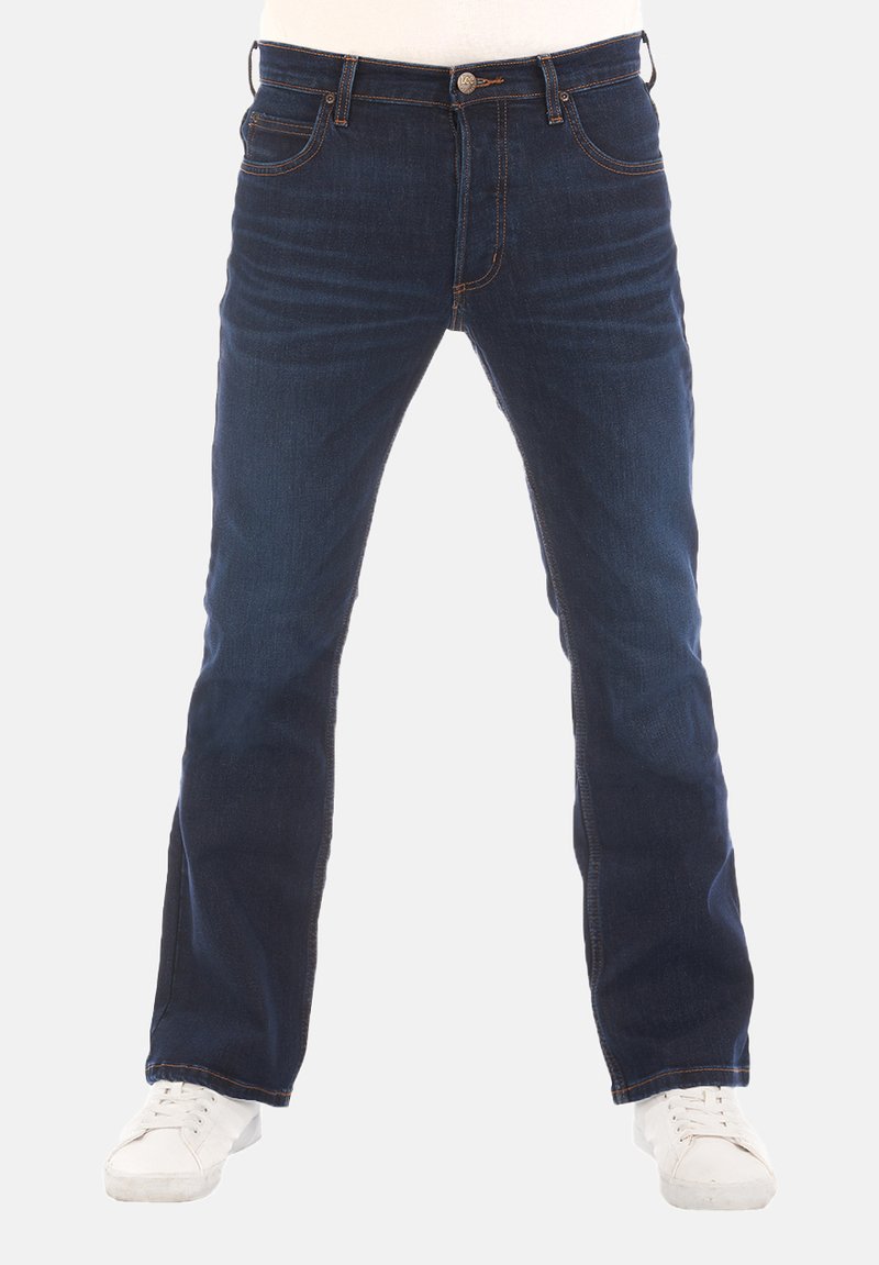 Donkerblauwe denim jeans met een recht model, vijf zakken, zichtbare stiksels en een metalen knoopsluiting. Witte sneakers gedragen.