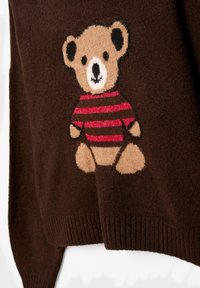 Rjava pletena majica z vezenim bež medvedom s črnim robom in rdeče črtasto srajco, mehka tekstura in rebrast rob.