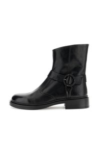 Bota de tobillo de cuero negro con punta redonda, detalle de correa lateral y un acento circular. Presenta una textura suave y un tacón de bloque de 2 pulgadas.