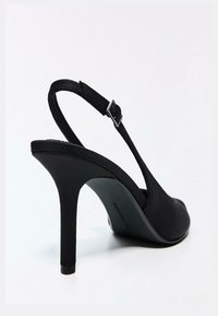 Pantof negru din satin cu toc înalt, dublu cu vârf ascuțit și toc stiletto subțire, de înălțime medie. Dispune de o cataramă metalică reglabilă.