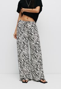 Zwarte en witte broek met wijde pijpen, gemaakt van zebradessin stof. Voorzien van een elastische tailleband met een trekkoord en een lichtgewicht, vloeiende pasvorm.