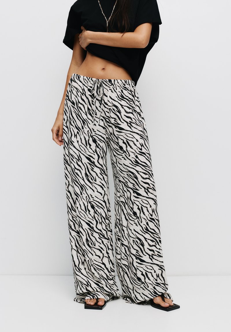 Zwarte en witte broek met wijde pijpen, gemaakt van zebradessin stof. Voorzien van een elastische tailleband met een trekkoord en een lichtgewicht, vloeiende pasvorm.