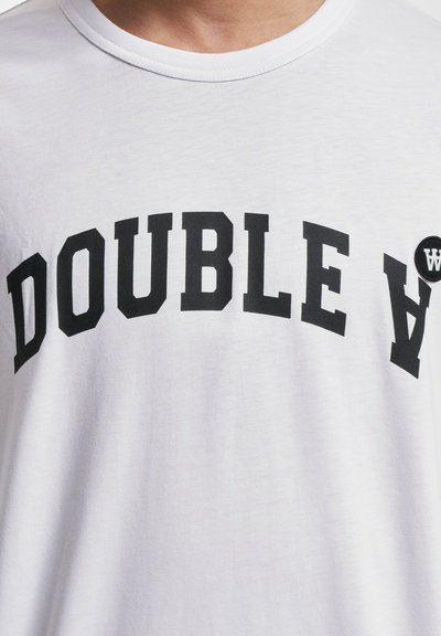 Valge puuvillane T-särk, millel on julge must tekst "DOUBLE A" kaarekujuliselt, väikese ümmarguse musta logo detailiga. Sile tekstuur.